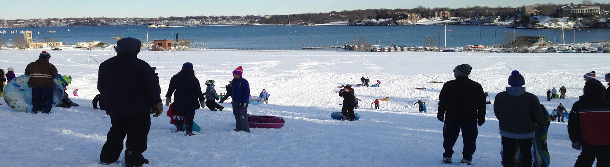 families snow sledding at fort adams in newport ri